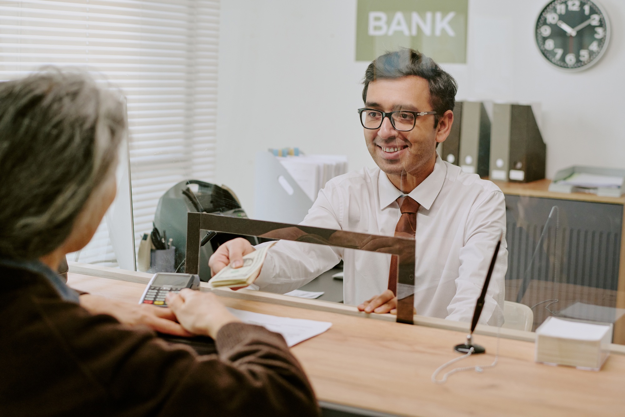 Bank Teller Smiling While Helping Customer