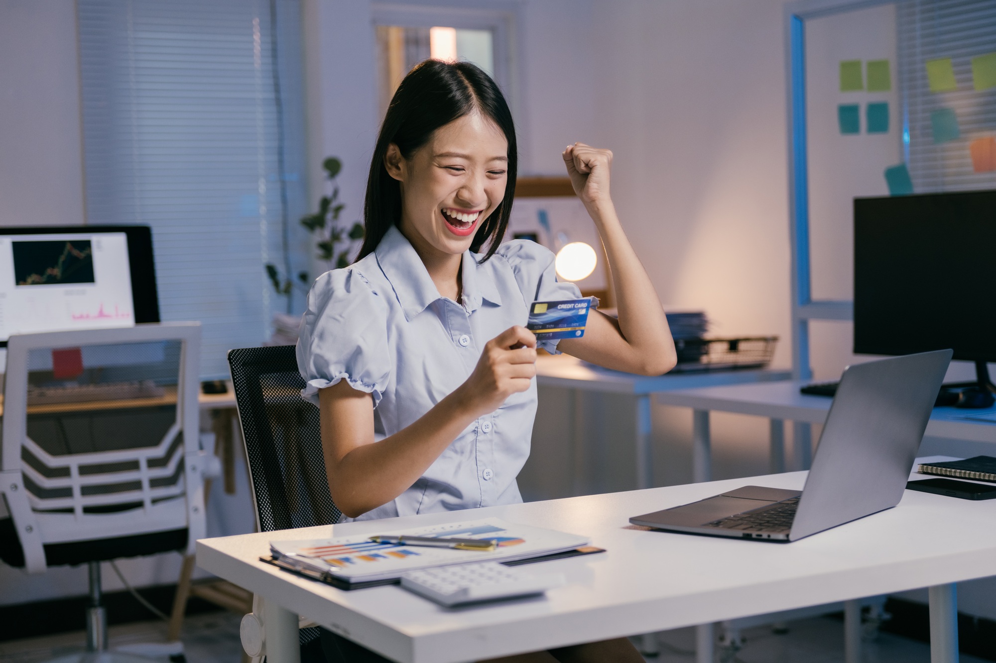 Happy businesswoman using laptop and credit card for online payment, celebrating financial freedom a