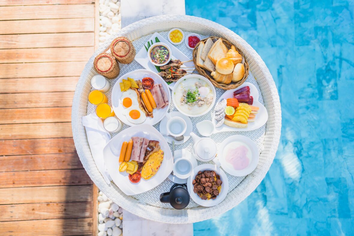 Floating breakfast set in tray with fried egg omelette sausage ham bread fruit milk juice coffee