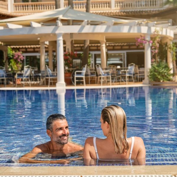 Couple resting in pool of resort hotel