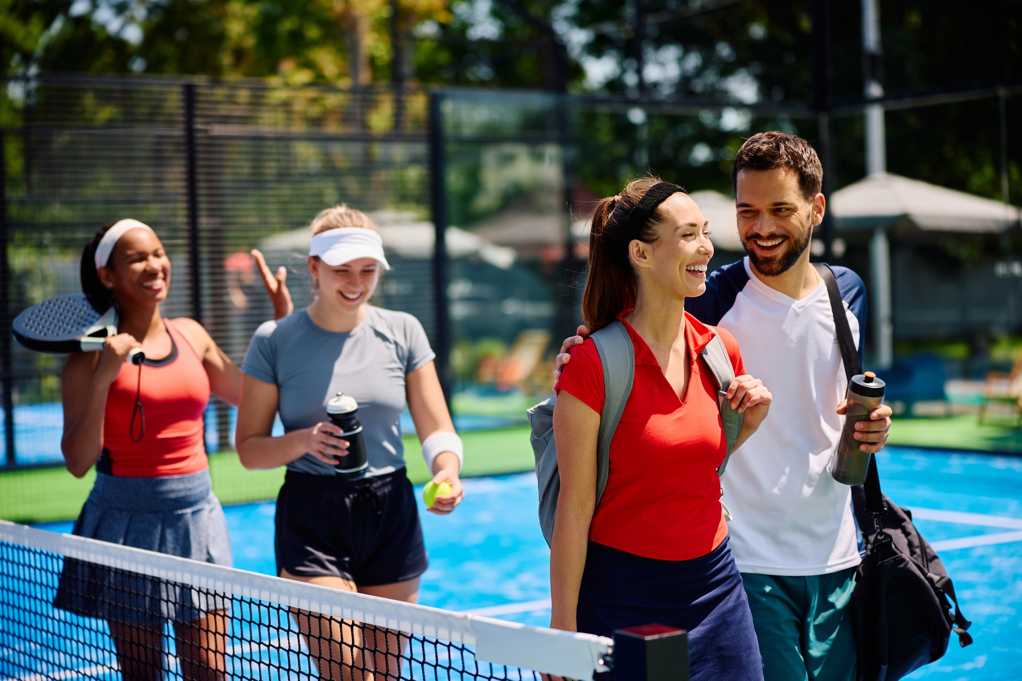 Group of happy friends leaving paddle tennis court after the match.