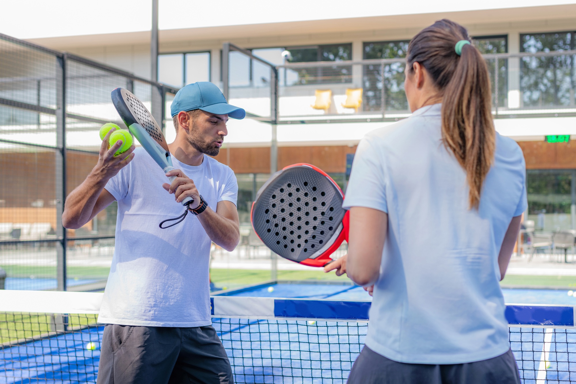 Padel coach with a student, learning techniques on the court for real progress