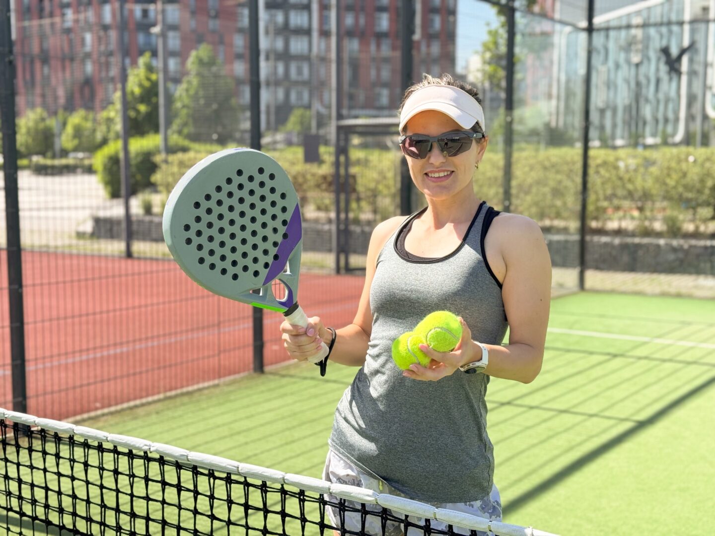 Portrait of active emotional woman playing padel tennis on open court in summer, swinging racket to