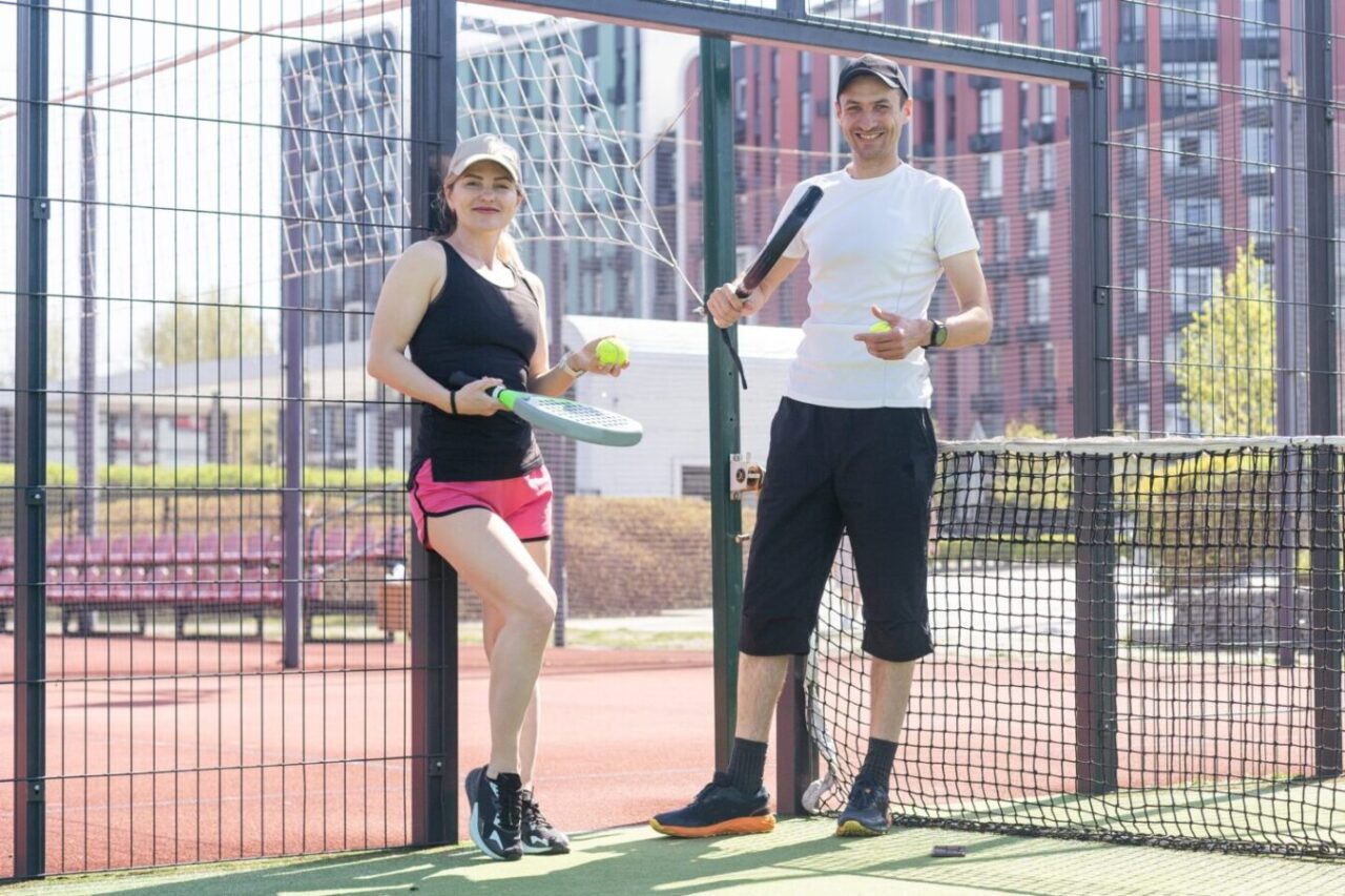 Sports couple with padel rackets posing on tennis court