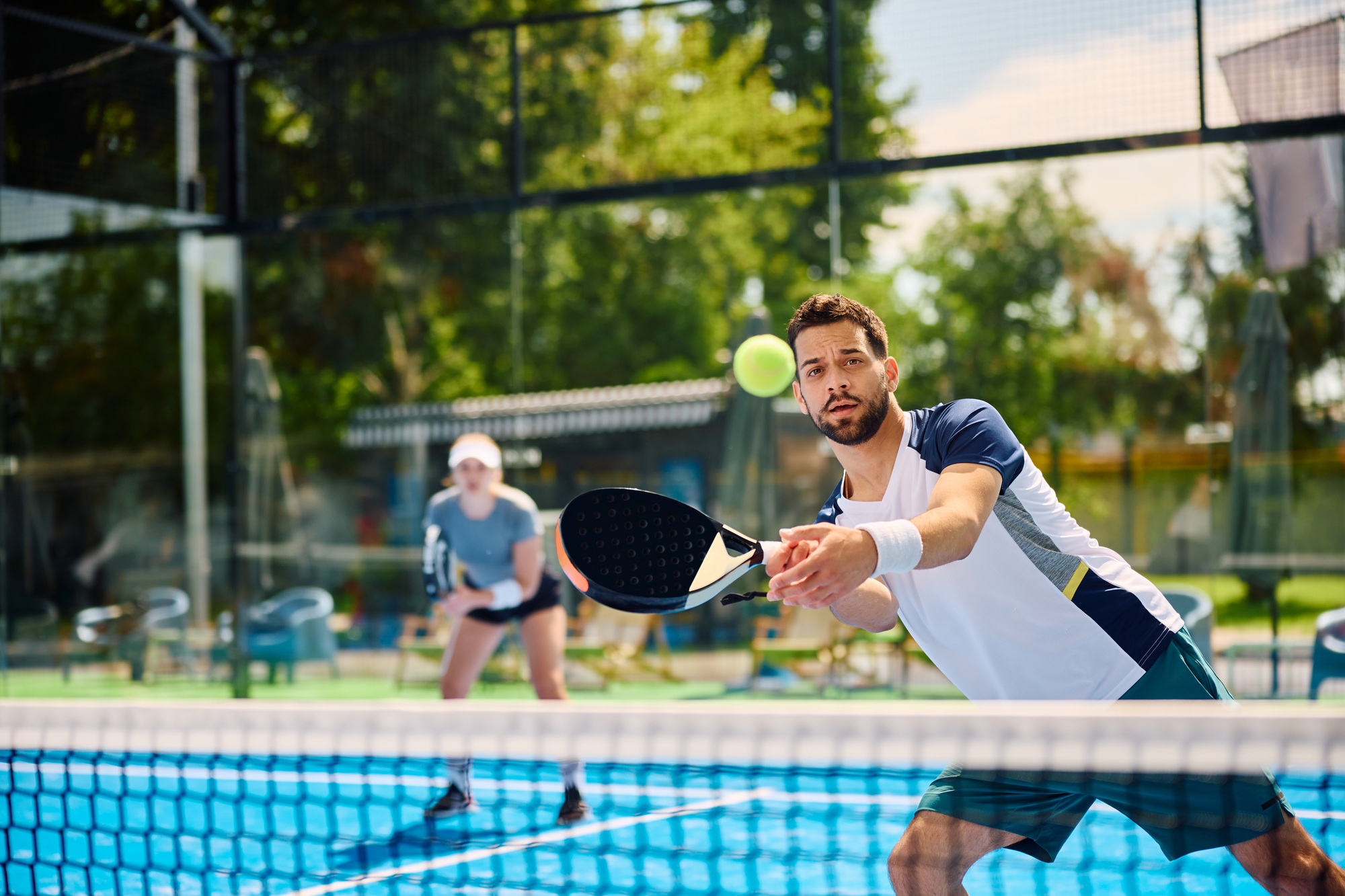 Young athletic man playing padel on outdoor tennis court.