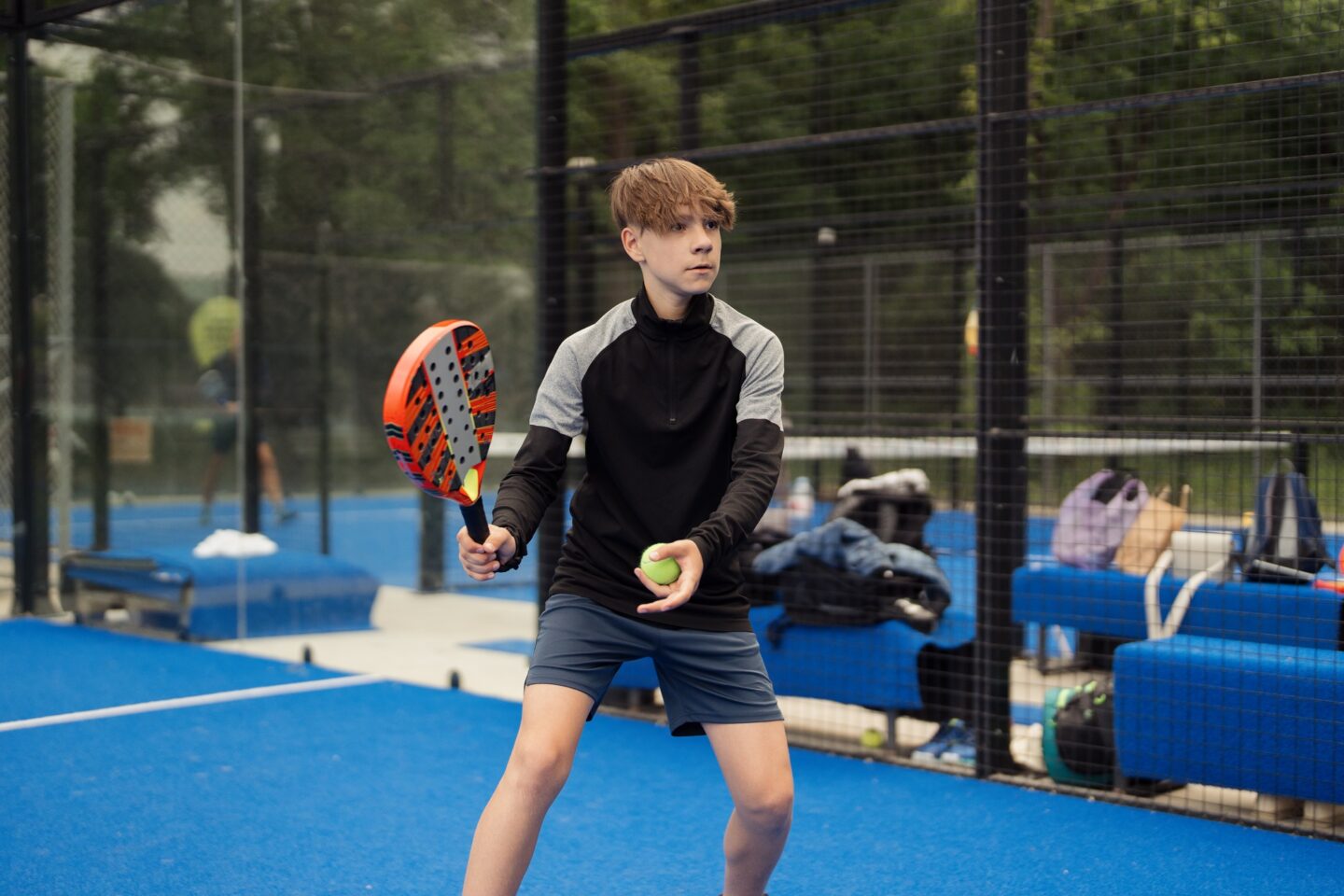 Young boy playing padel tennis on an outdoor court